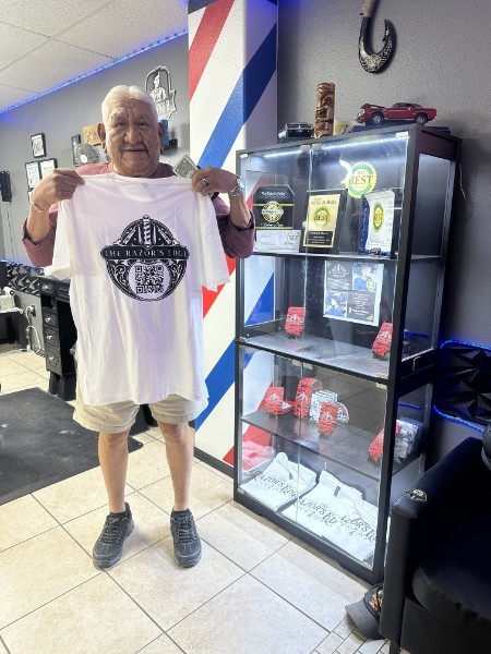 A client holding the new Razor's Edge T-shirt beside the awards case